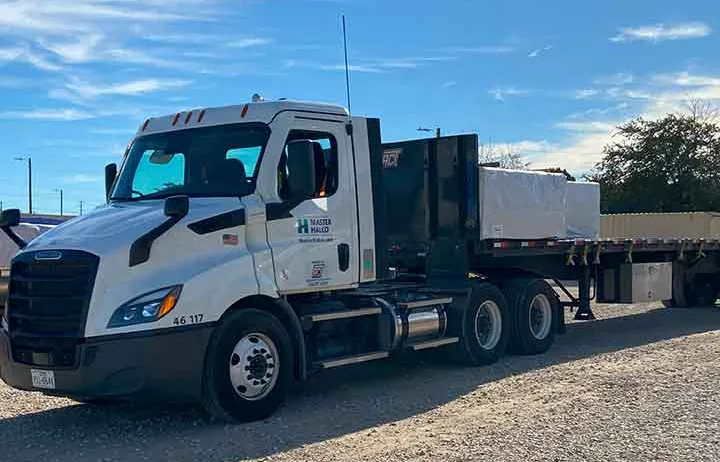 a work truck with flat bed trailer loaded with materials parked at a self storage facility
